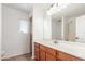 Bright bathroom featuring a wide mirror, neutral countertop, and wood-finished cabinets for a clean, modern aesthetic at 45080 W Buckhorn Trl, Maricopa, AZ 85139