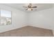 A bright, carpeted bedroom with a ceiling fan and a window offering natural light at 45080 W Buckhorn Trl, Maricopa, AZ 85139