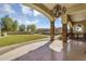 Backyard view from patio with covered travertine tile, stone pillars, and manicured green grass at 8325 W Cantera Ave, Peoria, AZ 85383
