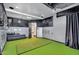 Golf simulator room features artificial turf, a padded bench, projector, and golf club storage at 8325 W Cantera Ave, Peoria, AZ 85383