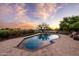 Backyard pool area with travertine patio, lounge chairs, lush desert landscaping, and sunset views at 9301 E Via Montoya --, Scottsdale, AZ 85255