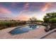 Inviting outdoor living area showcasing a travertine patio, pool, and lush desert landscaping at sunset at 9301 E Via Montoya --, Scottsdale, AZ 85255