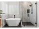 Bathroom featuring freestanding tub, glass shower, black fixtures, and window with shutters at 10415 E Rosemary Ln, Scottsdale, AZ 85255