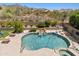 Backyard pool oasis with waterfall feature, slide, tanning shelf, and seating at 10415 E Rosemary Ln, Scottsdale, AZ 85255