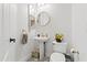 Stylish powder room with a pedestal sink, round gold mirror, and decorative tile floor at 10415 E Rosemary Ln, Scottsdale, AZ 85255