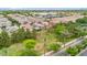 An aerial neighborhood shot features rows of tile-roofed homes next to a green space with palm trees and blue skies at 1069 S Nancy Ln, Gilbert, AZ 85296