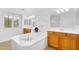 Bathroom featuring a soaking tub, wood cabinets, and dual sinks at 1069 S Nancy Ln, Gilbert, AZ 85296
