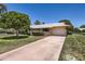 Charming single-story home featuring a well-manicured lawn, a two-car garage, and mature trees on a sunny day at 13631 N 103Rd Ave, Sun City, AZ 85351