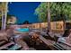Backyard at dusk featuring a pool, fire pit with chairs, and mature trees, creating a cozy outdoor space at 15841 N 23Rd Pl, Phoenix, AZ 85022