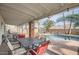 Outdoor patio seating area features a dining table, covered area, and a view of the sparkling pool and palm trees at 15841 N 23Rd Pl, Phoenix, AZ 85022