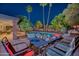Outdoor patio at night, featuring a dining table set for a meal, with views of the pool and lush landscaping at 15841 N 23Rd Pl, Phoenix, AZ 85022