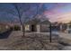 Charming single story home with desert landscaping and a two car garage underneath a vivid sunset sky at 16077 W Larkspur Dr, Goodyear, AZ 85338
