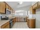 Functional kitchen with stainless steel appliances, light wood cabinets, and a view into an adjacent space at 16077 W Larkspur Dr, Goodyear, AZ 85338