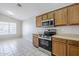 A well-lit kitchen featuring wood cabinetry, a stainless steel oven, and neutral countertops at 16077 W Larkspur Dr, Goodyear, AZ 85338