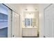 Bright bathroom featuring double sinks, decorative lighting, sliding closet doors, and a mirrored wall at 20427 W Mountain Sage Dr, Buckeye, AZ 85326