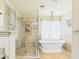 Bathroom featuring an elegant soaking tub, a glass-enclosed shower, and travertine tile at 2331 E Melrose St, Gilbert, AZ 85297