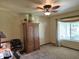 Carpeted bedroom featuring a wooden armoire, a ceiling fan, and a window with a view to the yard at 2331 E Melrose St, Gilbert, AZ 85297
