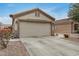 Beige two-car garage with a concrete driveway and low maintenance desert landscaping at 24009 W Antelope Trl, Buckeye, AZ 85326