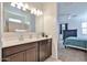 Bathroom with double sinks, dark cabinets, large mirror, and bedroom access at 30935 W Mulberry Dr, Buckeye, AZ 85396