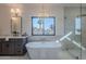 Bright bathroom featuring a soaking tub beneath a window, complemented by a glass-enclosed shower and elegant chandelier at 5525 E Waltann Ln, Scottsdale, AZ 85254