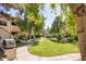 Lush community green space with mature trees, a walking path, landscaping, and outdoor grill at 6885 E Cochise Rd # 129, Paradise Valley, AZ 85253