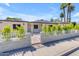 Beige home with a white picket fence, mature landscaping, and large green palm trees at 701 W Windsor Ave, Phoenix, AZ 85007