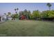 Large backyard with lush lawn, play structure, and shaded seating area at 7471 E Northern Ave, Scottsdale, AZ 85258