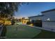 Tranquil backyard featuring a putting green, refreshing pool, and elegant outdoor lighting at twilight at 7471 E Northern Ave, Scottsdale, AZ 85258