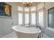 Bright bathroom features bay window, vintage style tub, chandelier, and neutral walls at 7471 E Northern Ave, Scottsdale, AZ 85258