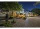 Beautiful night view of the home's facade with terracotta roof, lush plants and a brick-paved driveway at 7471 E Northern Ave, Scottsdale, AZ 85258