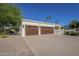 Spacious three-car garage with wooden doors and a wide driveway, surrounded by lush landscaping at 7471 E Northern Ave, Scottsdale, AZ 85258