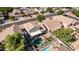 An aerial shot highlights a pool and patio, set among lush trees in a residential neighborhood at 7931 W Harmony Ln, Peoria, AZ 85382