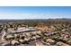 Aerial view showcasing a neighborhood, a school, and mountains in the distance under a bright sky at 7931 W Harmony Ln, Peoria, AZ 85382