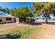 Rear view of the home with mature trees and a patio at 9863 W Country Club Ct, Sun City, AZ 85373