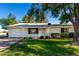 Charming single-story home with a well-manicured lawn, mature trees, and a welcoming front porch at 9863 W Country Club Ct, Sun City, AZ 85373