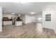 Bright, open-concept living room and kitchen area with wood-look tile flooring and stainless steel appliances at 9863 W Country Club Ct, Sun City, AZ 85373
