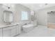 Bright bathroom featuring double vanity, stand alone tub, marble floors and countertops, and modern fixtures at 1229 N 106Th Pl, Mesa, AZ 85207
