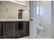Well-lit bathroom with dual sink vanity, and an enclosed toilet next to a door at 1624 N 77Th Gln, Phoenix, AZ 85035