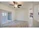 Living room with ceiling fan, sliding glass door to patio, and views of a kitchen at 1624 N 77Th Gln, Phoenix, AZ 85035