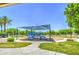 A blue playground with slides and climbing structure situated in a grassy park area under a shade structure at 1624 N 77Th Gln, Phoenix, AZ 85035