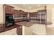Gourmet kitchen featuring dark wood cabinetry, granite countertops, and stainless steel appliances at 18322 W Sweet Acacia Dr, Goodyear, AZ 85338