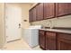 Laundry room with washer, dryer, cabinets, sink, and backyard access at 18322 W Sweet Acacia Dr, Goodyear, AZ 85338