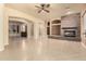 Spacious living room featuring stone fireplace, arched doorways, and neutral tile flooring at 18322 W Sweet Acacia Dr, Goodyear, AZ 85338