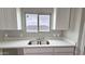 Kitchen featuring bright white cabinets, light countertops, and a stainless steel sink at 20419 W Mountain Sage Dr, Buckeye, AZ 85326
