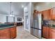 View of the kitchen with stainless steel refrigerator, brown cabinetry and view of the dining room at 2101 S Meridian Rd # 250, Apache Junction, AZ 85120