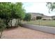 Landscaped backyard with gravel and mature trees, enclosed by a wrought iron fence overlooking a grassy area at 21675 N 61St Ave, Glendale, AZ 85308