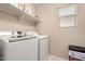 Bright laundry room featuring a white washer and dryer with open shelving at 2543 N 73Rd Dr, Phoenix, AZ 85035