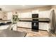 Bright kitchen featuring white cabinets, black countertops, stainless steel appliances, and wood-look tile flooring at 25955 W Deer Valley Rd, Buckeye, AZ 85396