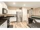 Well-lit kitchen with stainless steel refrigerator, white cabinets, and black countertops, open to dining area at 25955 W Deer Valley Rd, Buckeye, AZ 85396