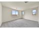This spacious bedroom has multiple windows providing lots of natural light and neutral carpet flooring at 37549 W San Clemente St, Maricopa, AZ 85138